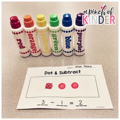 some crayons and markers are next to a sheet of paper that says dot & subtract