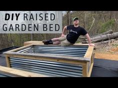 a man sitting on top of a wooden bed in the middle of a forest with text overlay that reads diy raised garden bed