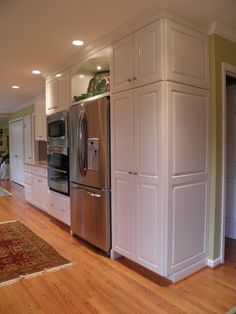 a large kitchen with white cabinets and stainless steel refrigerator freezer combo in the center