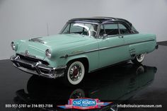 an old car is sitting on a black surface in front of a white wall and floor