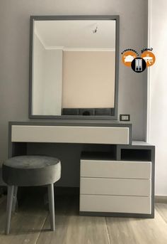 a white and grey dresser with a mirror on it's wall above a stool