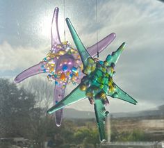 a glass starfish hanging from the side of a window with beads on it's body