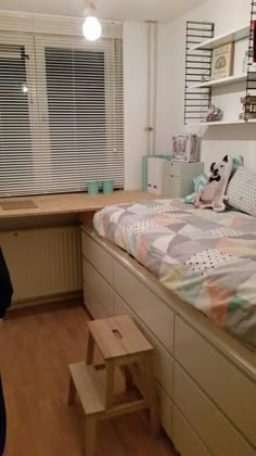 a bed room with a neatly made bed next to a window and a wooden floor