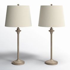 two lamps are sitting side by side on a white surface, one is turned off and the other has a beige shade