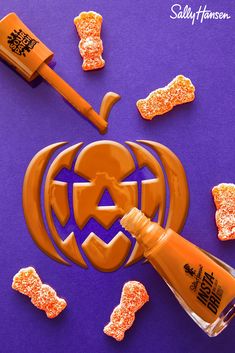 an orange liquid bottle sitting on top of a purple surface next to halloween candies