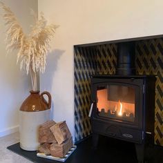 a fire place sitting next to a vase with some dry grass on top of it