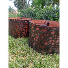 three metal planters sitting in the grass