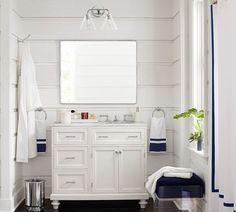 a white bathroom with blue accents on the vanity and towels hanging from the rack above it