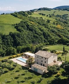 an aerial view of a house in the middle of a lush green field with trees