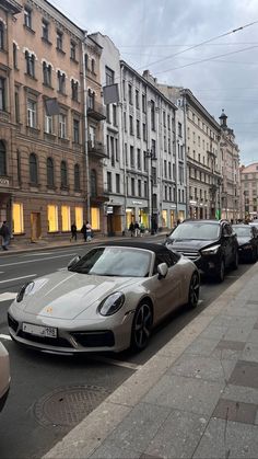 a row of parked cars on the side of a road next to tall buildings in a city