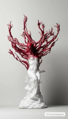 a white sculpture with red branches on it