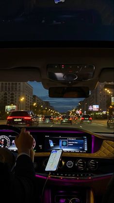 the interior of a car is lit up with purple lights and there are cars driving down the street at night