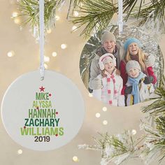 an ornament hanging from a christmas tree with two family photos on it and lights in the background