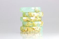 stack of green and gold bracelets against a white background