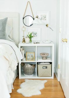 a bedroom with a white bed and some baskets on the shelf in front of it