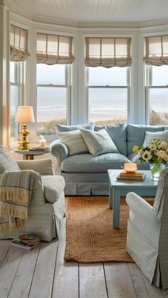 a living room filled with furniture next to two large windows covered in shades of blue