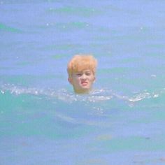 a boy swimming in the ocean with his head above water