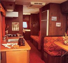 the kitchen and living area of an rv with wood paneling, red carpeted flooring and walls