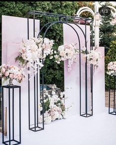 an outdoor wedding setup with flowers on the arch and white roses in vases at the end