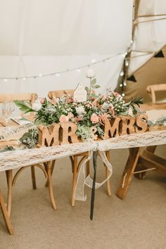 a wooden table topped with flowers and mr and mrs signs