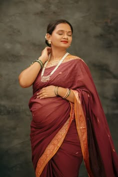 a woman wearing a maroon sari and gold jewelry