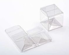 two clear plastic boxes sitting next to each other on a white surface with one open and the other closed