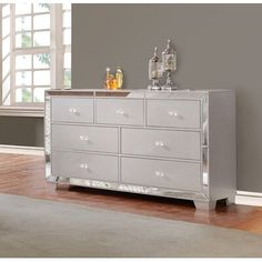 a silver dresser sitting in a room next to a window