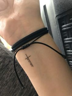 a woman's wrist with a small cross tattoo on the left side of her arm