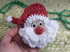 a hand holding a crocheted santa clause ornament with beads on it