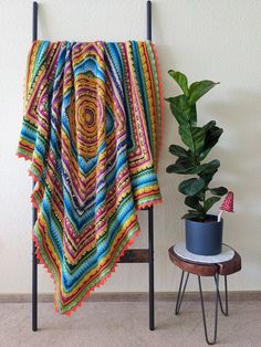 a potted plant sitting next to a blanket on a chair in front of a wall