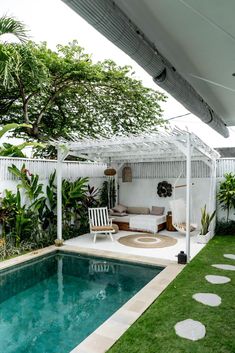 a small pool in the middle of a backyard with a white pergolated roof