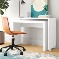 a white desk with a chair next to it and a potted plant in the corner