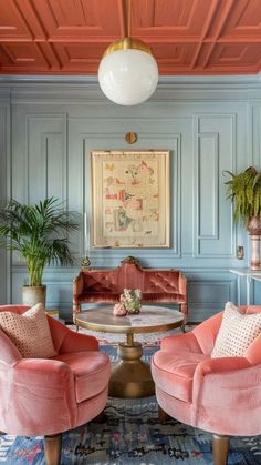 a living room filled with pink furniture and potted plants on top of a table