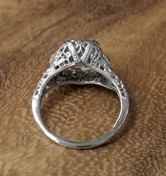 an antique style diamond ring sitting on top of a wooden table