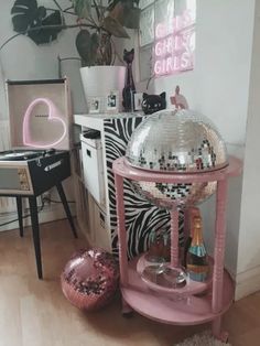 a pink disco ball stand in the corner of a room next to a chair and table