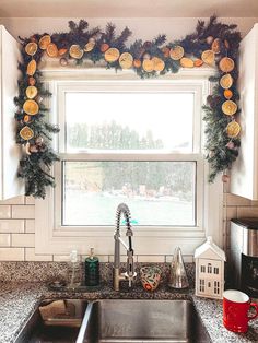 a kitchen sink sitting under a window covered in christmas decorations