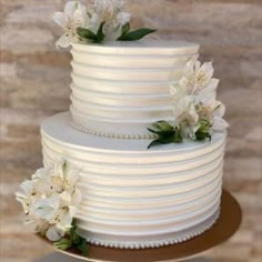 a three tiered cake with white flowers on top