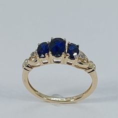 This Handmade Sapphire and Diamond Ring has been carefully crafted in 10k Yellow Gold, Authentic White Diamonds  and Authentic Sapphire. This delicate ring would make an amazing birthday/any occasion gift. Ring will be shipped to you in an elegant gift box and it can resized at no extra cost. Once the ring has been mailed a tracking shipping number will be provided to you. Sapphire Measurements: 1 Sapphire: 6.0 mm x 4.0 mm 2 Sapphire: 5.0 mm x 3.0 mm Diamond Measurements: 2 Diamonds, each stone Gold Sapphire Ring, September Birthstone, Blue Sapphire Rings, Delicate Rings, Multi Stone, Multi Stone Ring, Blue Rings, 10k Gold, Gold Style