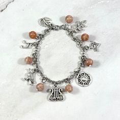 a bracelet with charms on it sitting on top of a snow covered ground in front of a white background