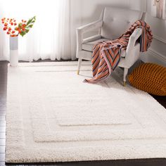 a white rug in a living room with a chair and vase on the floor next to it