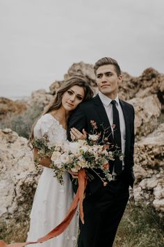 a man in a suit and tie standing next to a woman wearing a wedding dress