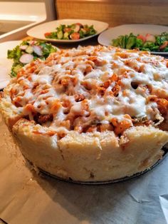 a pizza sitting on top of a table next to plates of salad and other food