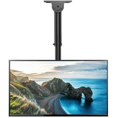 a flat screen tv sitting on top of a metal pole next to an ocean and rock formation