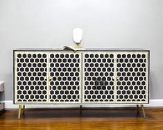 a white and black cabinet sitting on top of a hard wood floor next to a wall