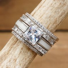 a white gold ring set with a princess cut diamond surrounded by baguettes and diamonds