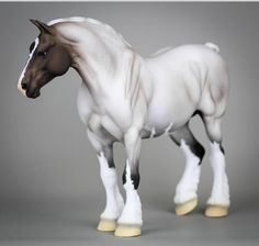 a white and brown horse standing on top of a gray floor