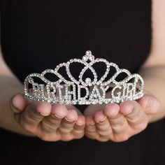 a woman holding a tiara in her hands with the word birthday girl written on it