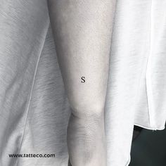 a person with a small tattoo on their arm and the word s in black ink