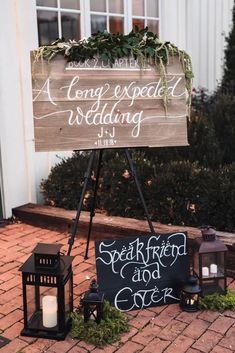 a wooden sign sitting on top of a sidewalk next to a lantern and some candles