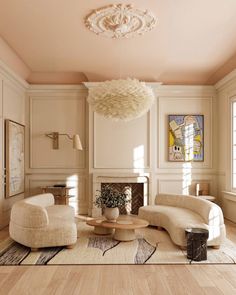 a living room filled with furniture and a chandelier hanging from the ceiling over a fire place